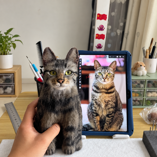 Custom tabby wool felt cat figure held beside a tablet showing the reference pet