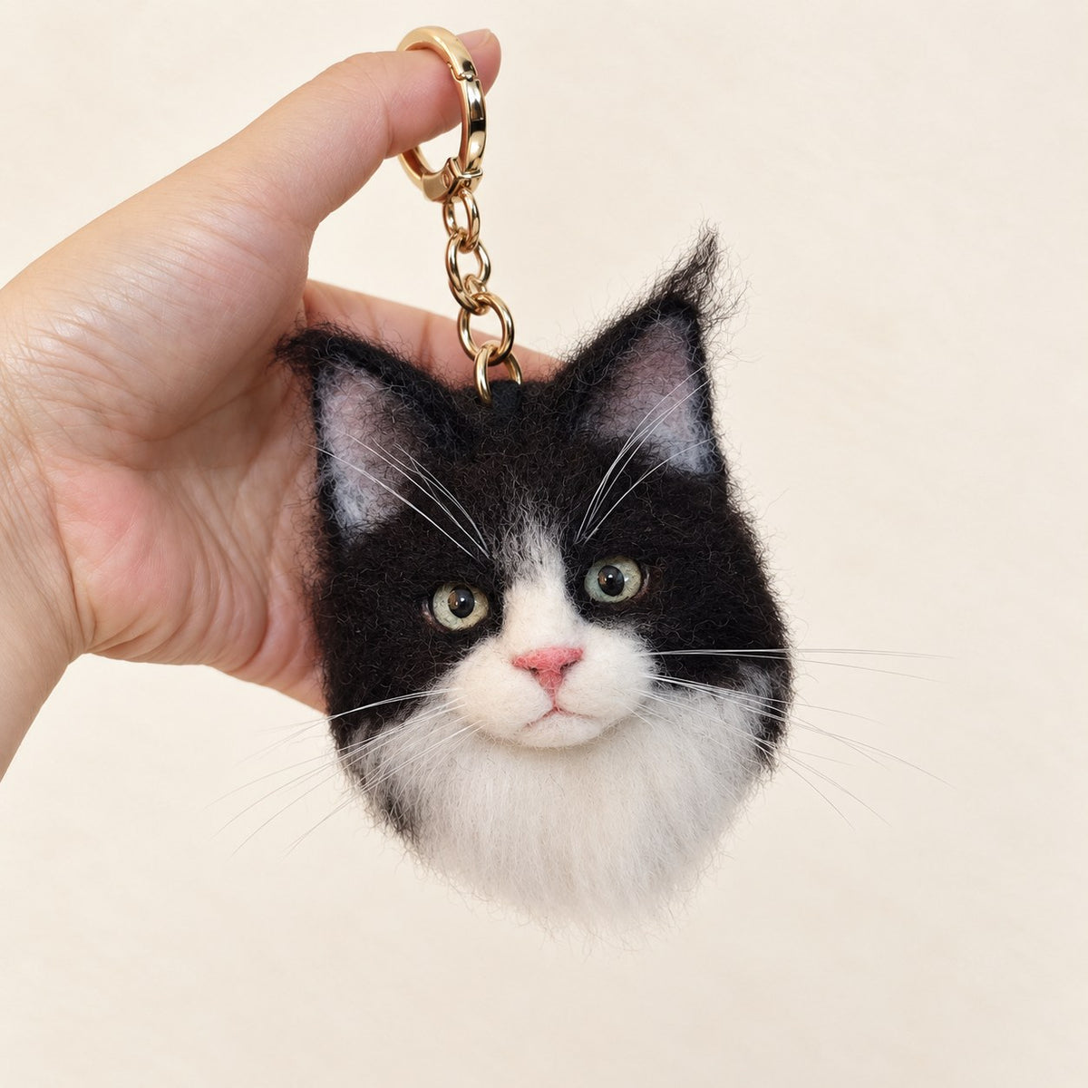 Handmade wool-felt black-and-white cat charm on a keyring, front view