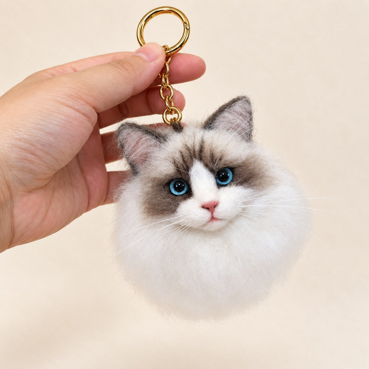 Handmade wool-felt fluffy light cat charm on a keyring, front view