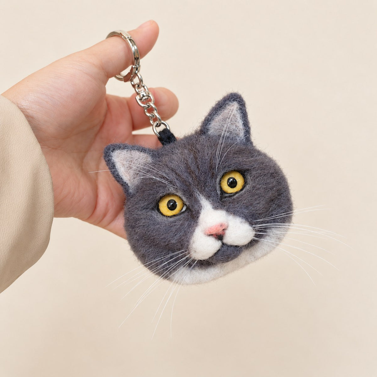Three-quarter view of a handmade wool-felt gray-and-white cat charm