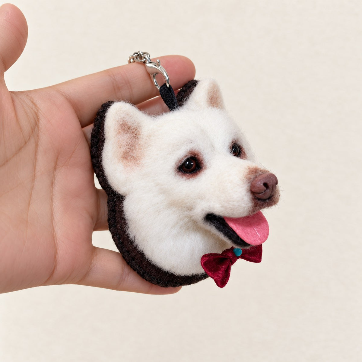 Three-quarter view of a handmade wool-felt white dog charm