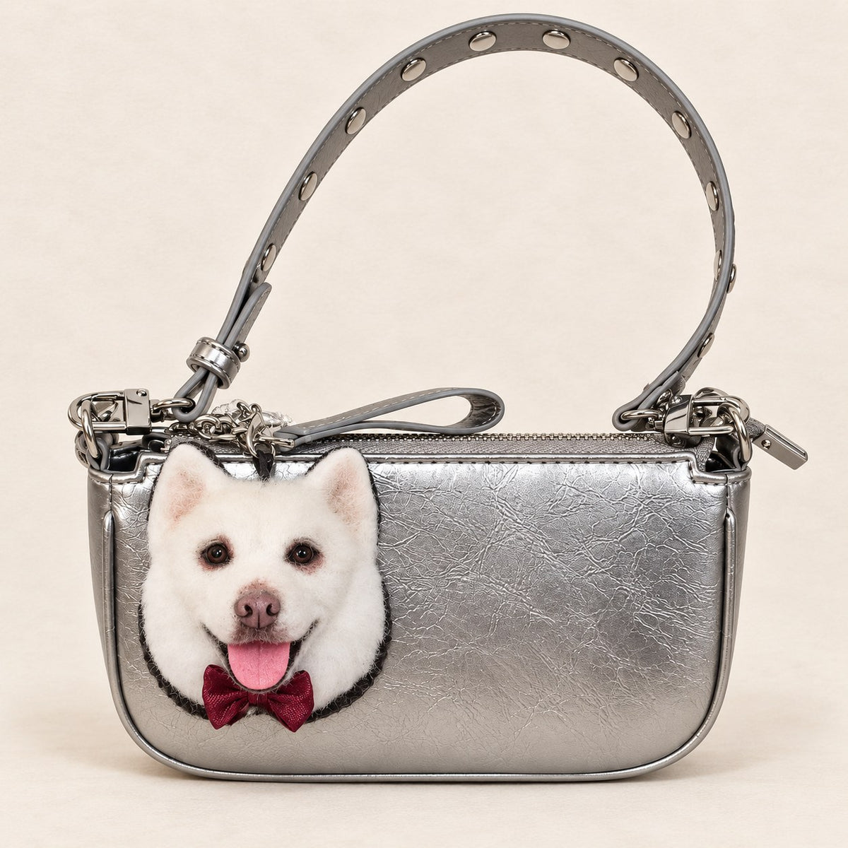 Handmade wool-felt white dog charm clipped to a silver bag, front view