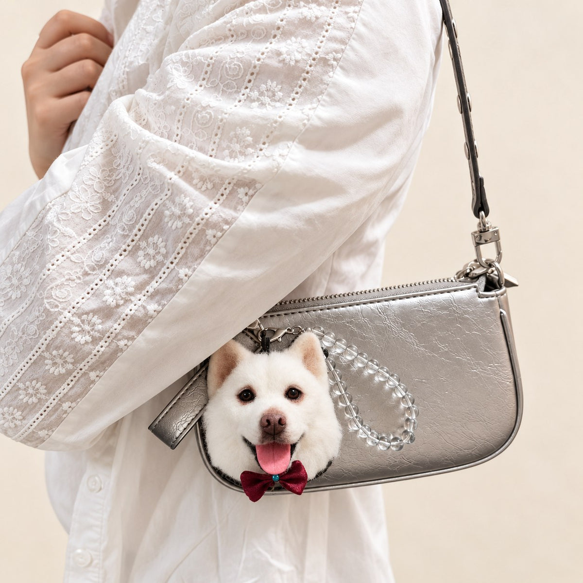 Handmade wool-felt white dog charm worn on a shoulder bag