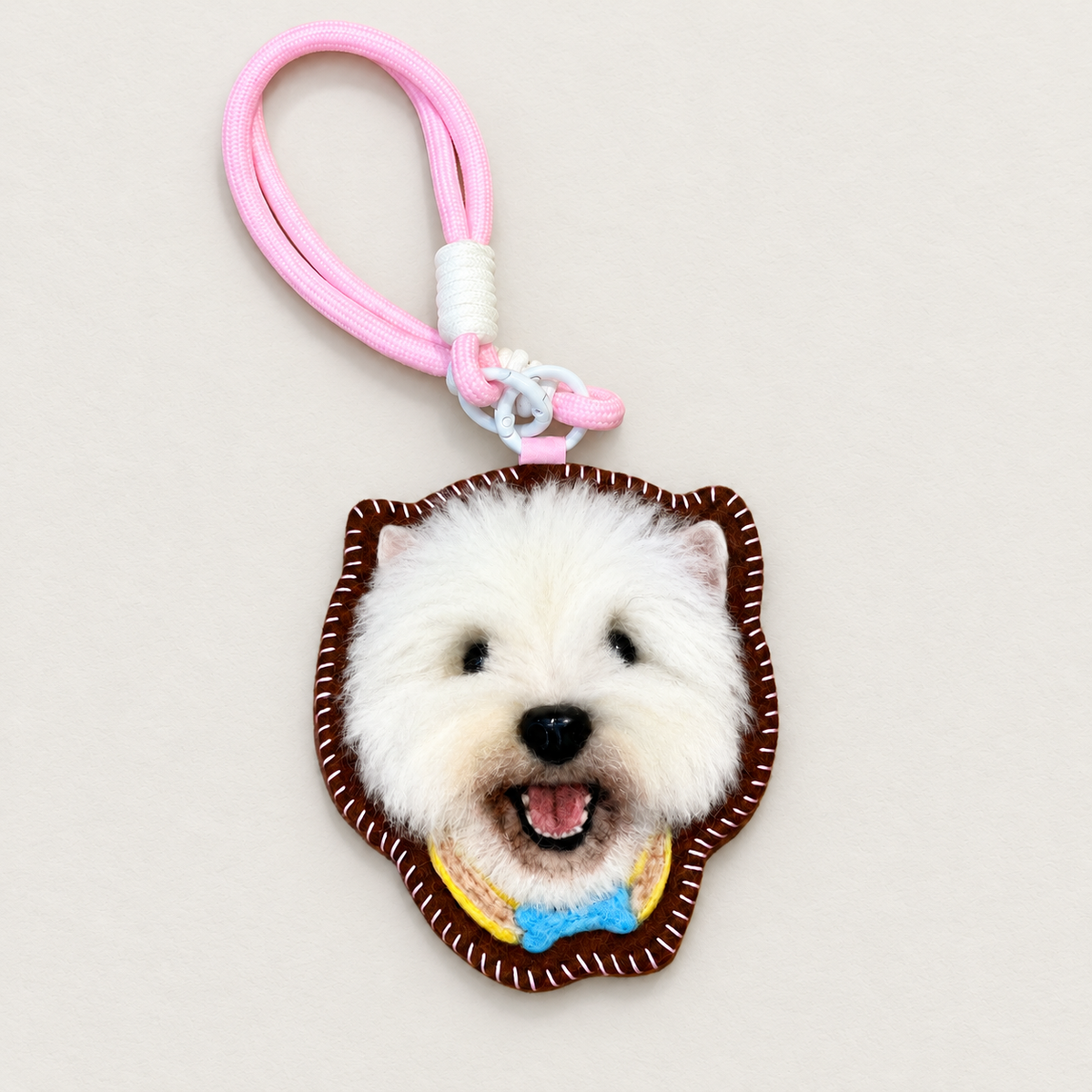 Handmade wool-felt white dog charm with pink strap, front view