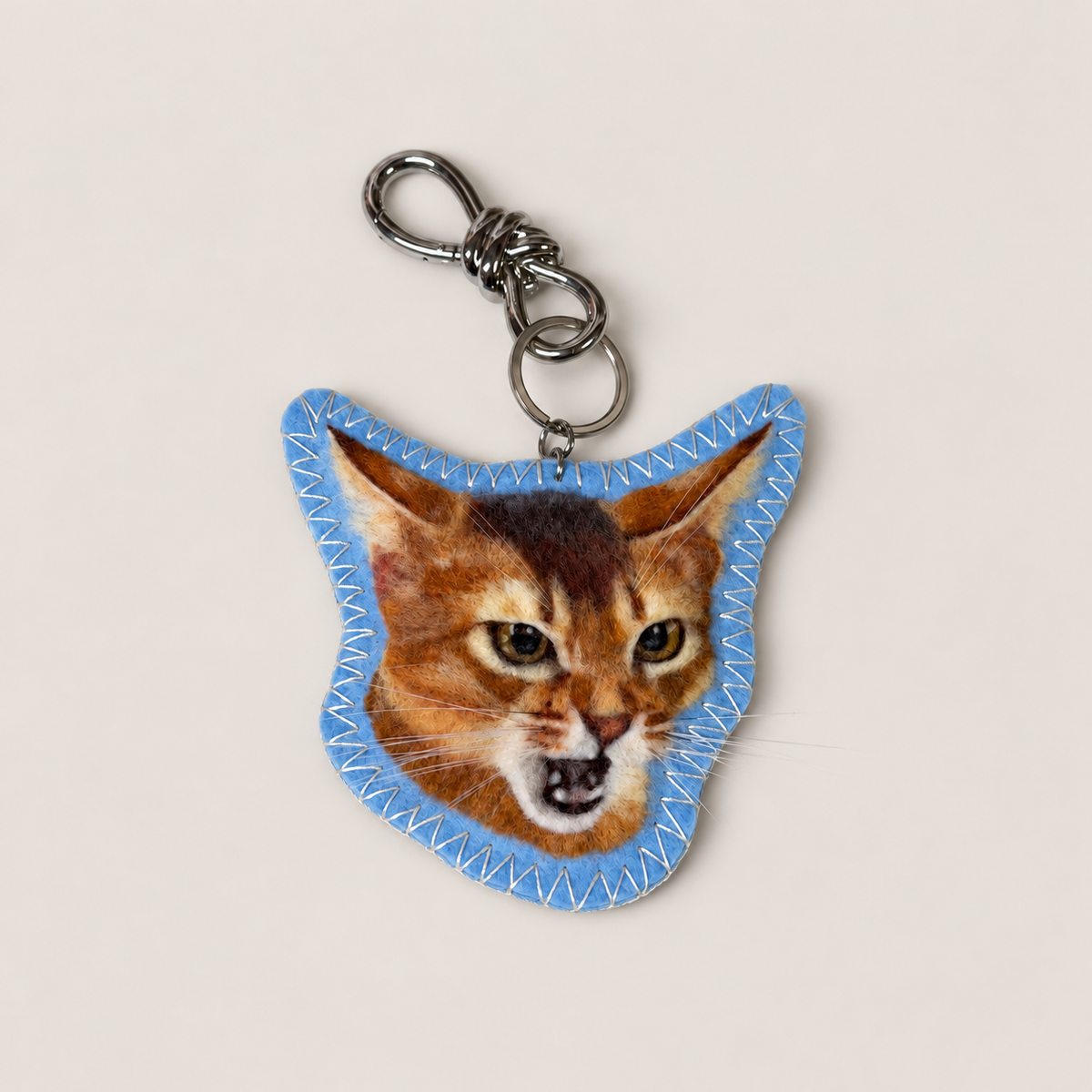 Close-up of a handmade wool-felt brown cat charm on a clasp