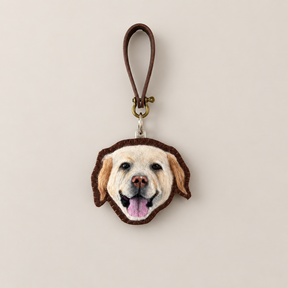 Handmade wool-felt cream dog charm with leather strap, front view